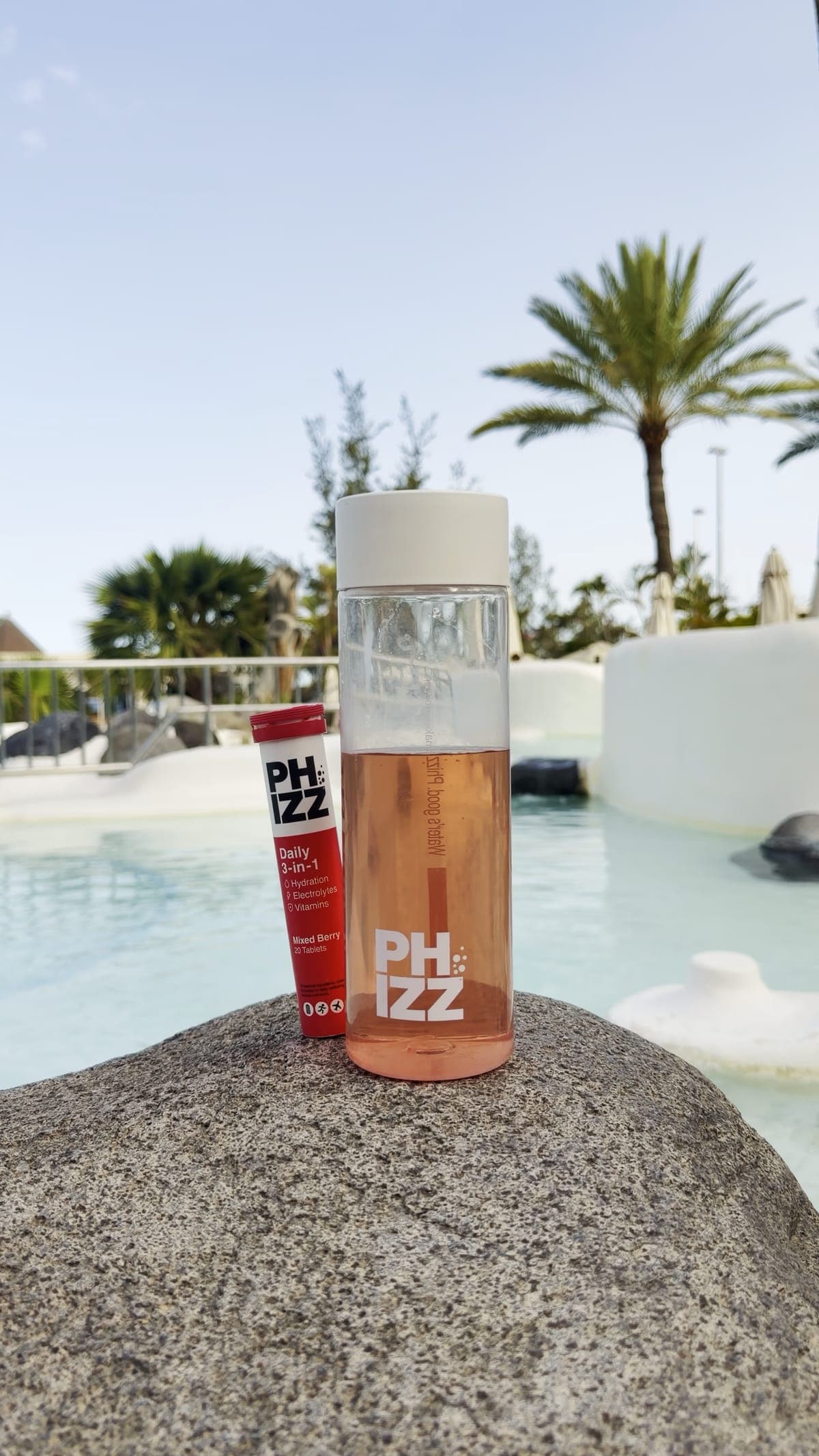 A Phizz bottle and tube of tablets on a rock beside a pool