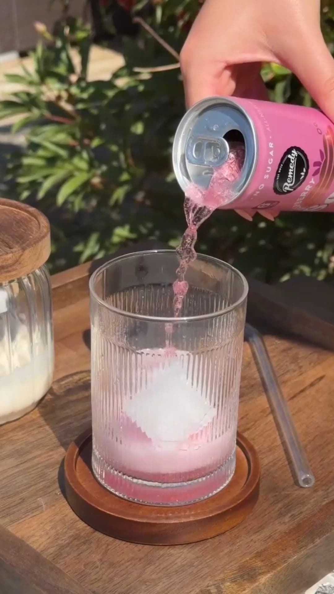 Remedy Raspberry Sodaly being poured over ice in a garden