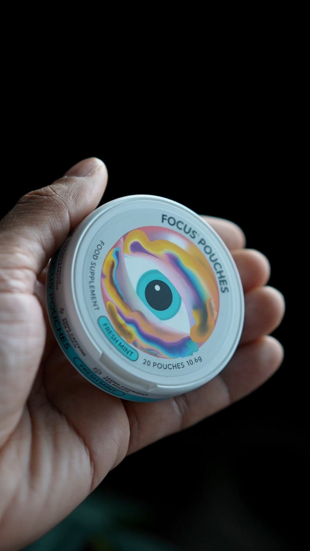 A close-up of a hand holding a tin of Focus Pouches